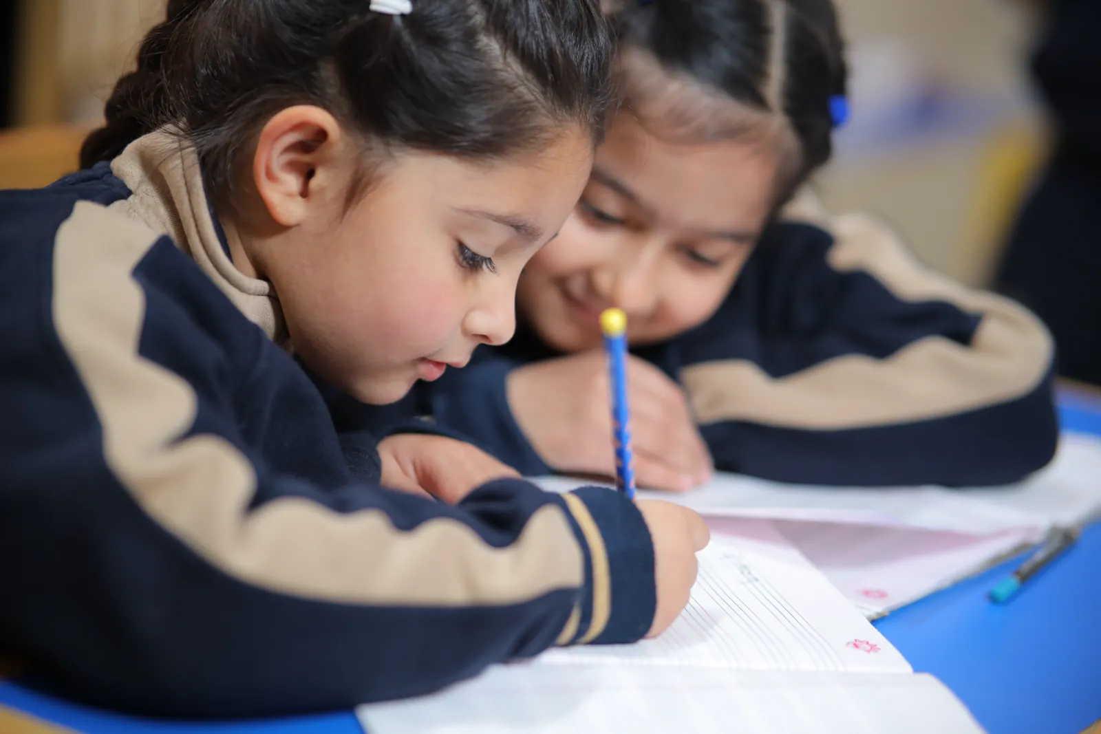 Two learners drawing together at a desk.