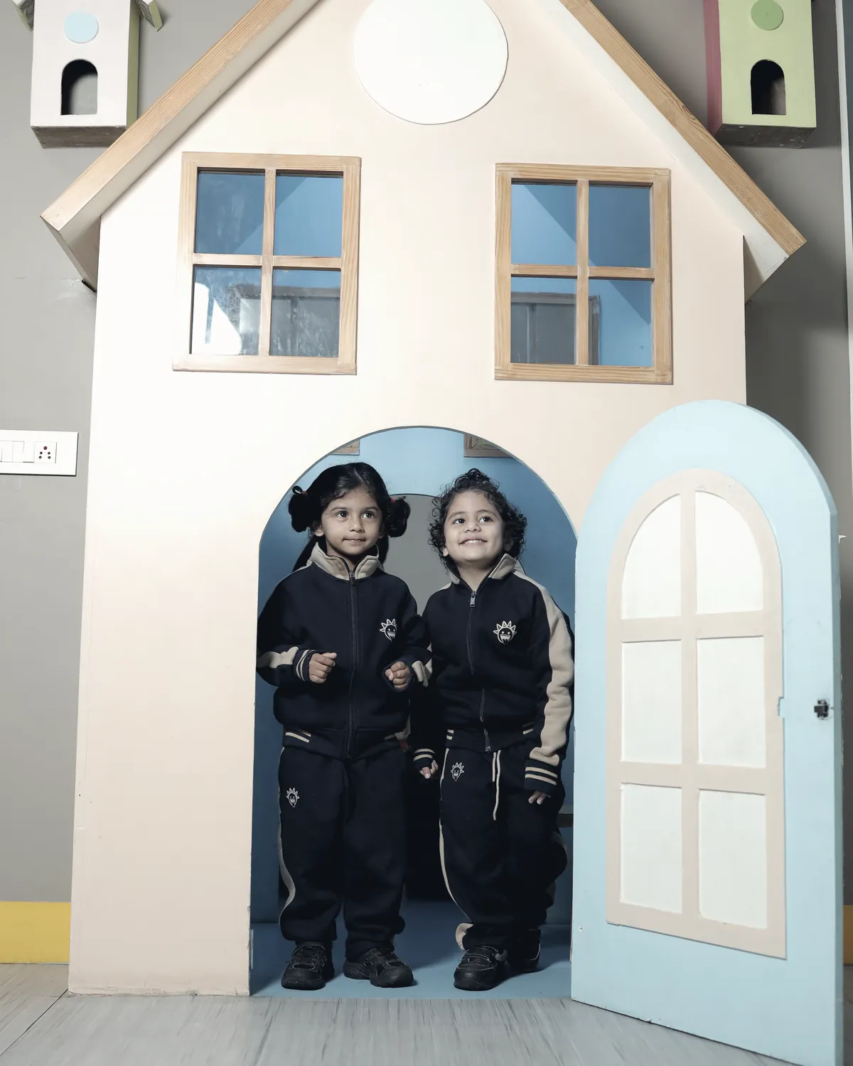 Two learners standing in the doorway of the wooden playhouse.