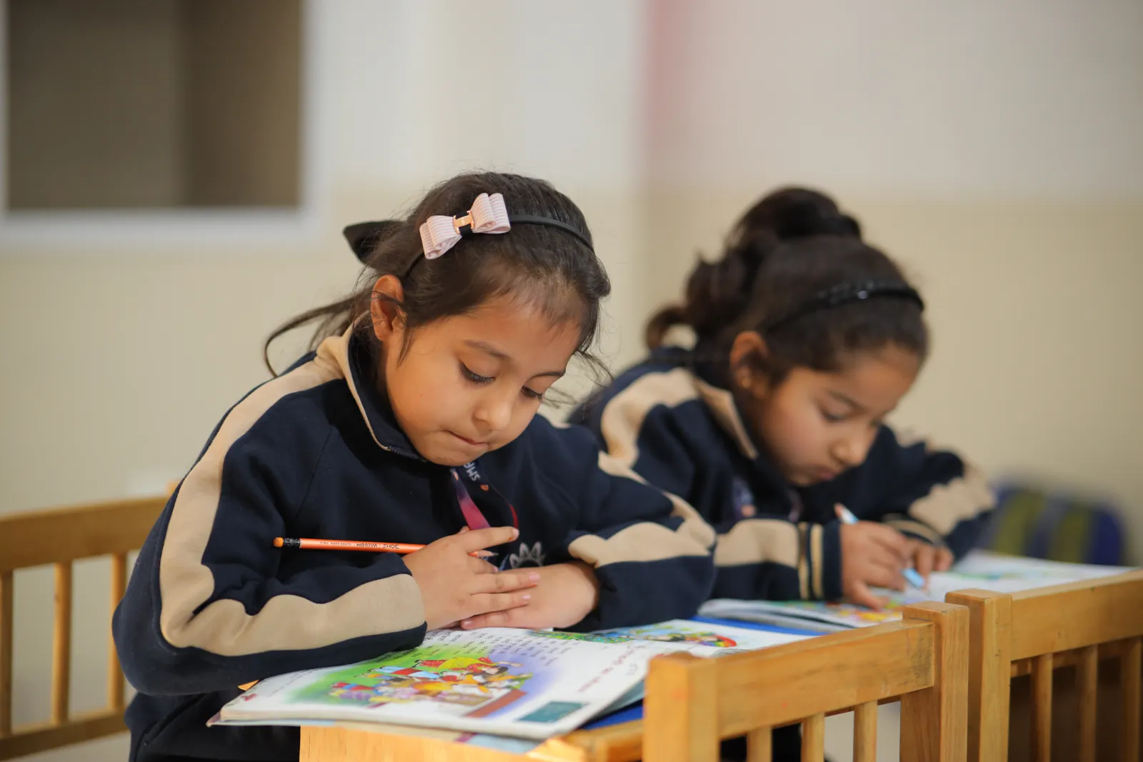 A learner at a desk, drawing beside an open picture book.