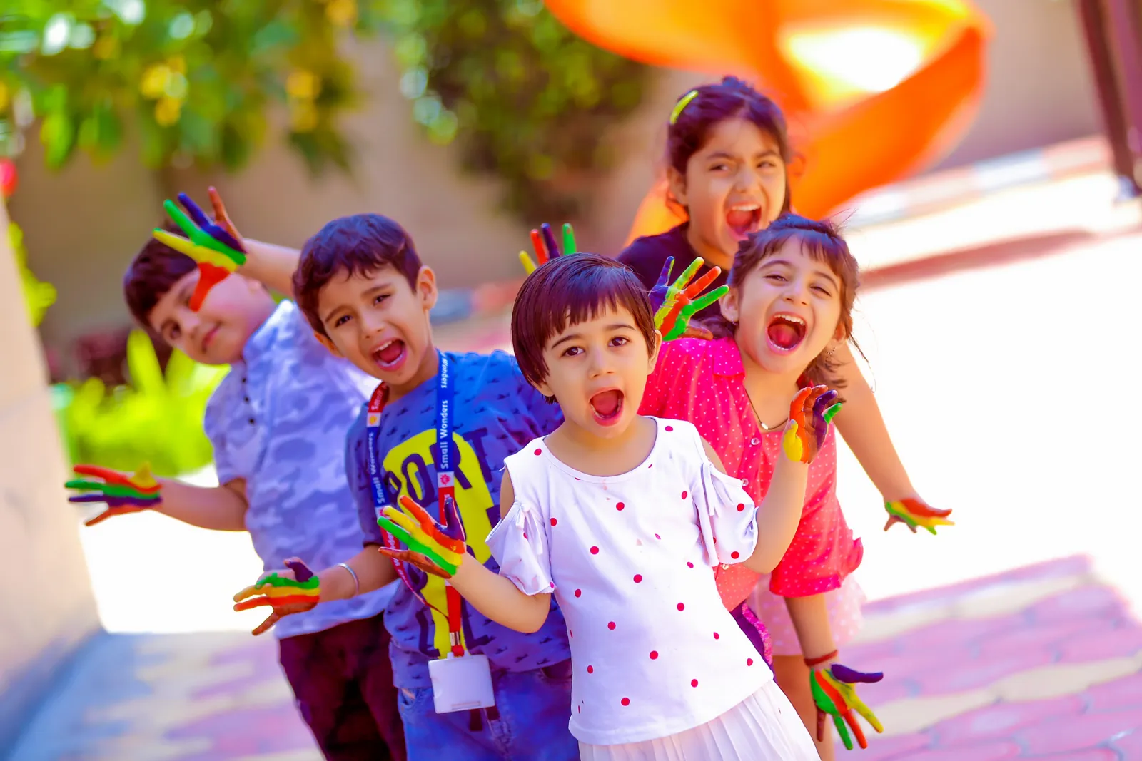 A group of learners laughing, hands painted in bright colours.
